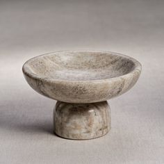 a small white bowl sitting on top of a table next to a black object in the background