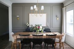 a dining room table with black chairs and white flowers on the table in front of it