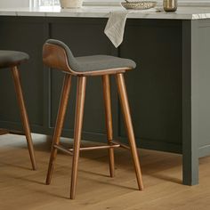 two stools in front of a kitchen island with marble counter tops and wooden legs