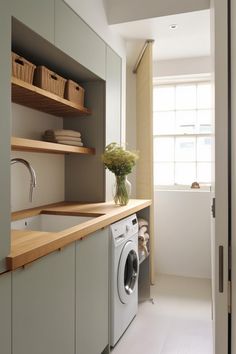 a washer and dryer in a small room with open shelves on the wall