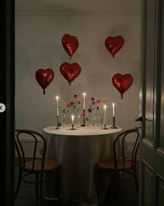 the table is set with candles and heart shaped balloons