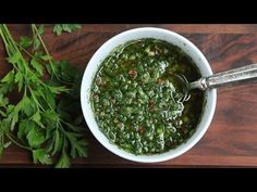 a white bowl filled with green vegetables on top of a wooden table next to parsley