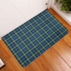 a brown and green plaid door mat sitting on top of a wooden floor next to a white door