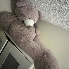 a teddy bear sitting on top of a microwave oven next to a white wall and ceiling