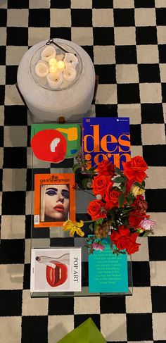 flowers, candles and magazines on a black and white checkered floor