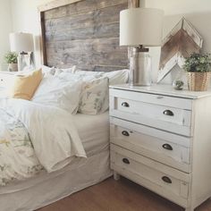 a white bed sitting next to a wooden headboard on top of a dresser in a bedroom