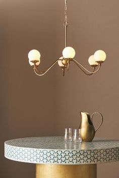 a table with a vase, pitcher and glasses on it in front of a brown wall