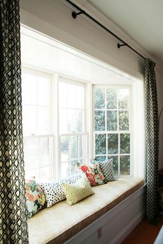 a window seat with many pillows on it