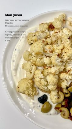 a white plate topped with cauliflower and olives