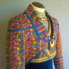 a mannequin wearing a colorful jacket and dress with buttons on the collarline