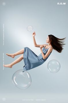 a woman in a blue dress is floating through the air with bubbles and soap bubbles