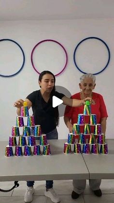 two women standing behind a table with cans on it