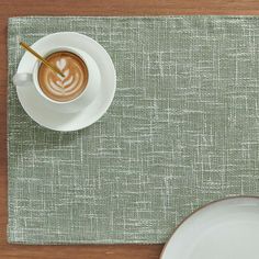 a cup of cappuccino on top of a table next to a plate