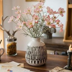 a vase filled with pink flowers sitting on top of a table next to a candle