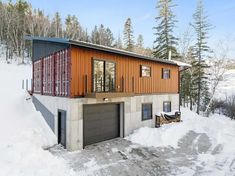 a house made out of shipping containers sitting on top of snow covered ground with trees in the background