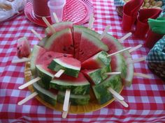 watermelon slices and toothpicks arranged on a plate at a picnic table