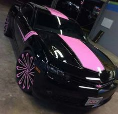 a black car with pink stripes parked in a garage