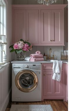 a washer and dryer in a small room with pink cabinets on the wall