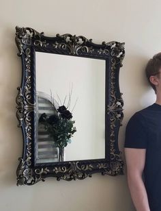 a man standing next to a wall with a large mirror on it's side