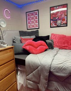 a bed with pink and grey pillows on top of it