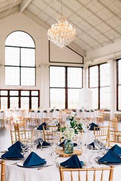 the tables are set with blue napkins and gold chairs for an elegant wedding reception