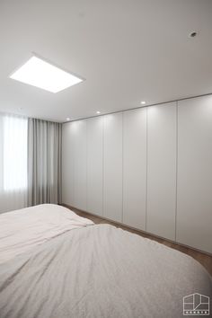 an empty bedroom with white walls and wooden flooring is pictured in this image, there are closets on the far wall