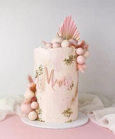 a pink and gold wedding cake decorated with pom - poms, seashells and shells