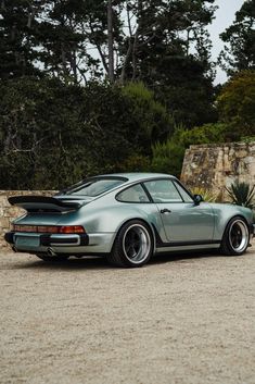 a silver porsche parked in front of some trees