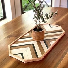 a small potted plant sitting on top of a wooden tray covered in geometric designs