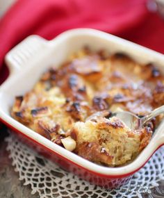 a red casserole dish filled with food and a spoon in it on a doily