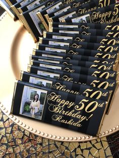 a table topped with lots of black and gold place cards on top of a plate