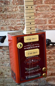 an electric guitar hanging from the side of a brick wall