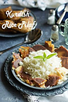 a plate with rice and meat on it next to silverware, spoons and utensils