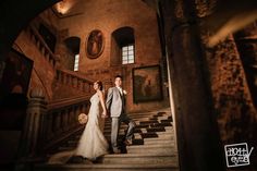 a bride and groom walking down the stairs at their wedding reception in an old building