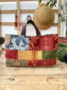 a multicolored purse sitting on top of a wooden table next to potted plants