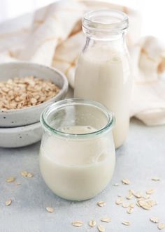 two bowls of oatmeal next to a bottle of milk