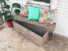 a wooden bench sitting on top of a porch next to a planter filled with flowers