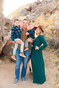 a man, woman and two young boys posing for a photo in the desert with rocks