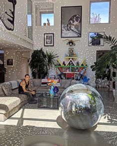 a man sitting in the middle of a living room filled with furniture and pictures on the walls