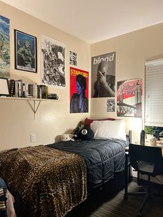 a bedroom with posters on the wall and a leopard print bed spread across the room