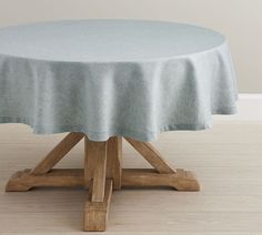 a round table with a light blue cover on it's top and wooden legs