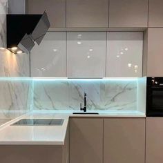 a modern kitchen with marble counter tops and white cupboards, along with an oven