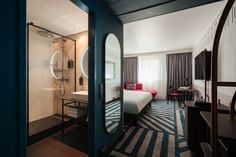 a hotel room with a bed, desk and mirror in the doorway to another room