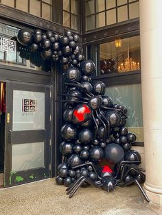 an art installation in front of a building that has been decorated with black and red balloons