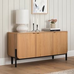 a wooden sideboard with two lamps and a painting on the wall