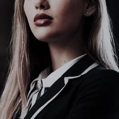 a woman with long blonde hair wearing a black and white striped shirt looking off to the side