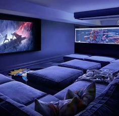 a room that has some couches in front of the screen and two large screens on the wall