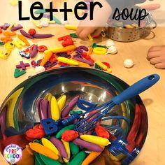 a bowl filled with lots of colorful plastic letters sitting on top of a wooden table