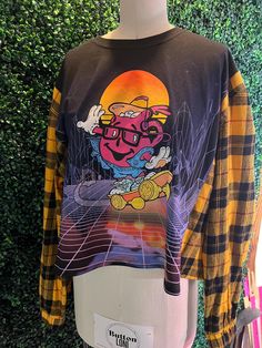 The Koolaid Man BUSTED outside of his own Tshirt and into a flannel! (lol)  This cool shirt is a one of a kind! If you like it, buy now or cry later.  Listed as a size Large, but would fit XL as well! Thanks for shopping our handmade and reworked fashions!  Your supporting a dream here! ✨ Retro Long Sleeve Tops With Graphic Design, Retro Graphic Design Tops For Fall, Grunge Graphic Design Tops For Fall, Urban Graphic Tops For Fall, Urban Graphic Design Tops For Fall, Vintage Relaxed Fit Flannel Top, Vintage Flannel Relaxed Fit Top, Oversized Black Flannel Top, Vintage Flannel Top With Relaxed Fit