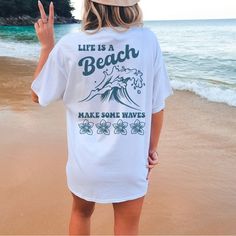 Tshirt Is Soft And Unisex Sizing For Loose Fit. For A Tighter Fit Size Down One. Life Is A Beach So Make Some Waves Design On Back Of White Tshirt And Front Pocket Has Make Some Waves Design. White Vsco T-shirt With Text Print, White Summer T-shirt With Text Print, Vsco Style Short Sleeve T-shirt With Text Print, Vsco Style T-shirt With Text Print, White Pre-shrunk T-shirt For Loungewear, Vsco Style Text Print Short Sleeve Top, Summer Slogan T-shirt For Loungewear, White Letter Print T-shirt For Loungewear, White Vsco Tops With Text Print